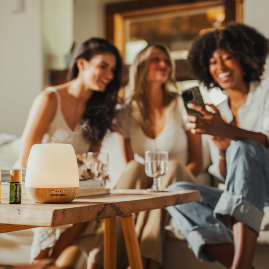 three smiling friends sitting near pyurvana essential oil and diffuser