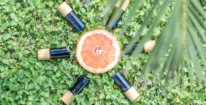 sliced orange surrounded by pyurvana essential oils on green grass