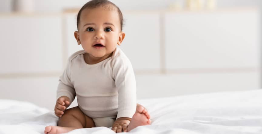 cute baby sitting on a bed and smiling