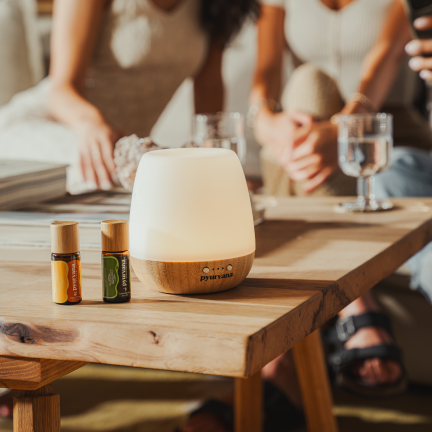 pyurvana essential oils and diffuser on a table beside the girls seating on a sofa