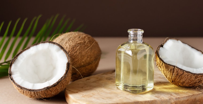 essential oil in a small glass bottle on the wooden deck along with coconut